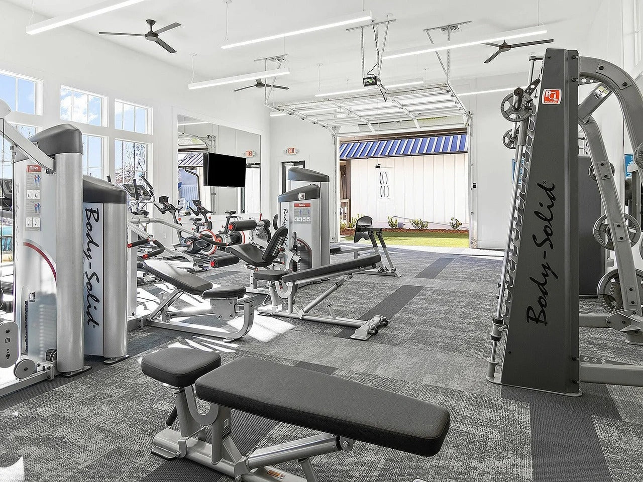 Gym interior with various exercise machines and equipment.