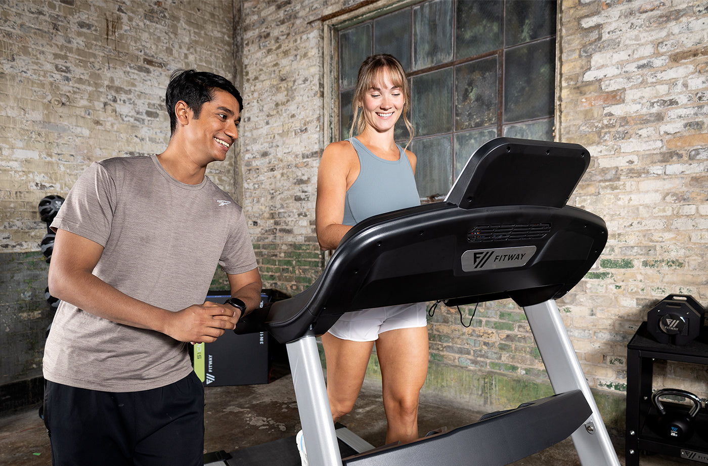 Man and woman using a Fitway 1500t treadmill in a brick-walled room