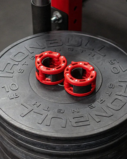 Stack of weight plates with red weight markers on a black Iron Bull Strength branded plate.