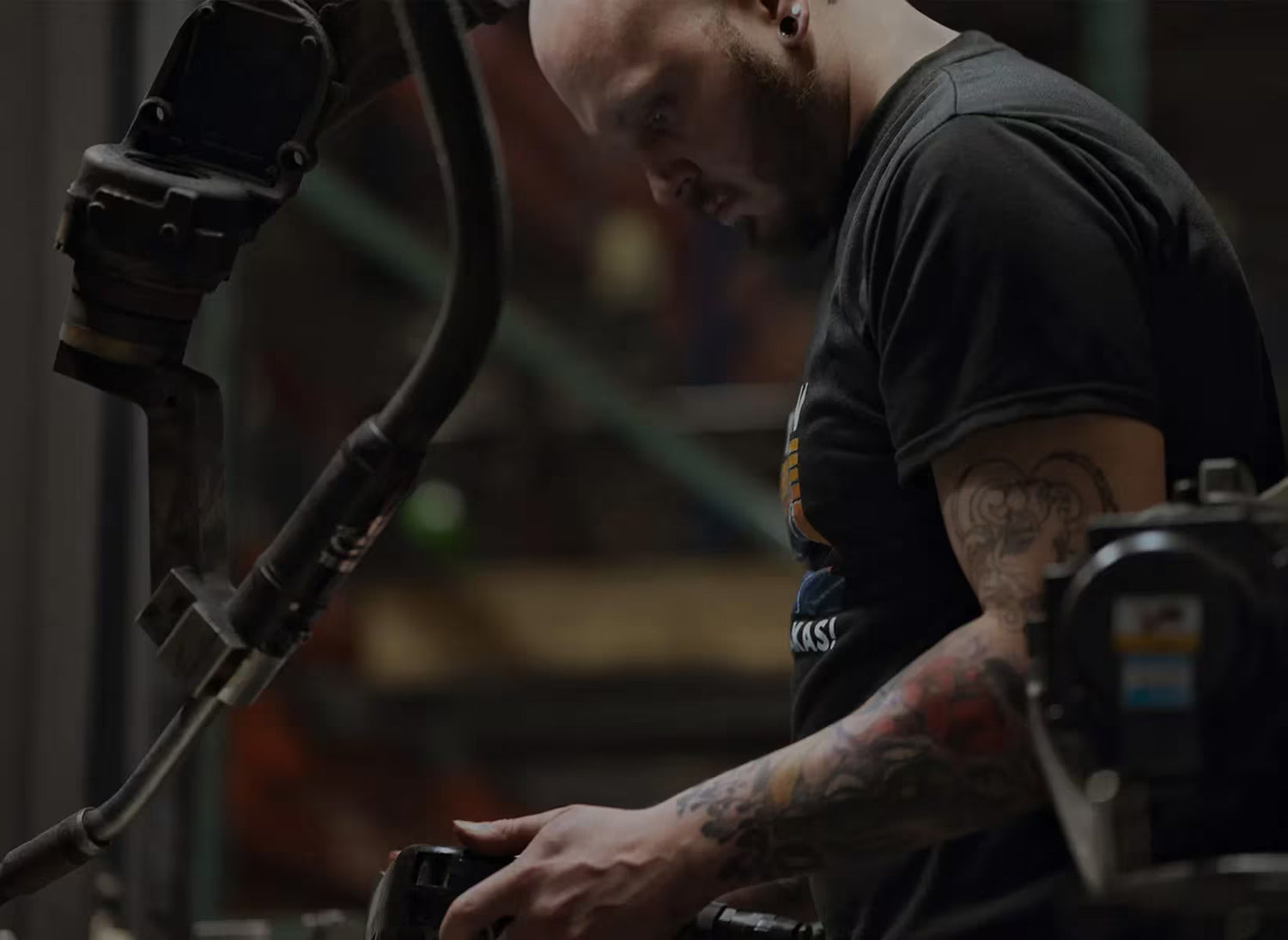 Person working on a piece of machinery with tattoos visible