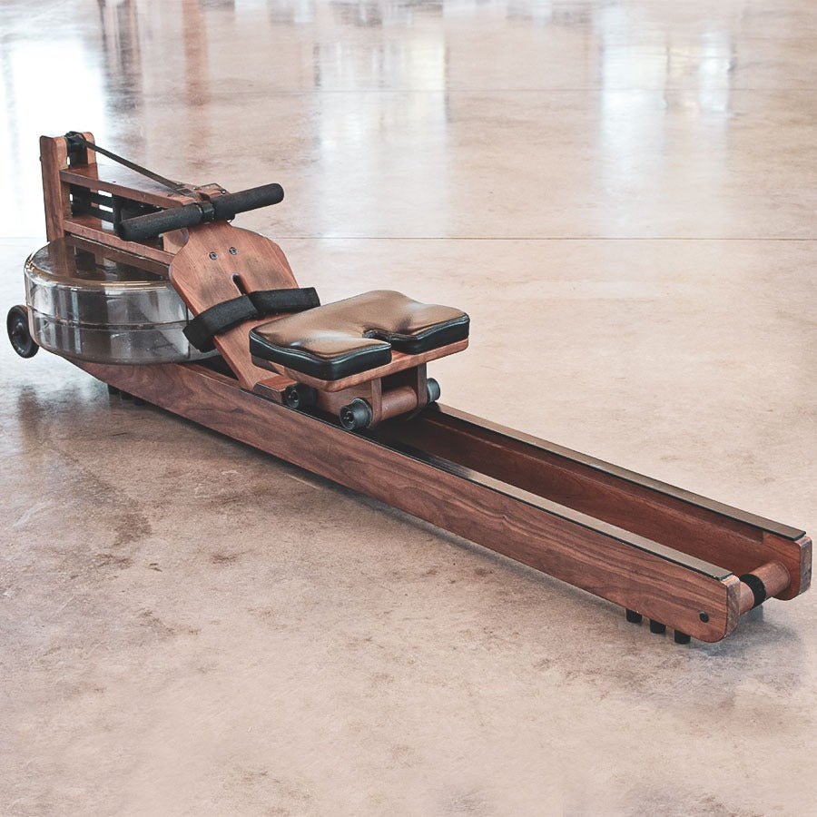 Wooden rowing machine on a concrete floor with a light-colored wall in the background