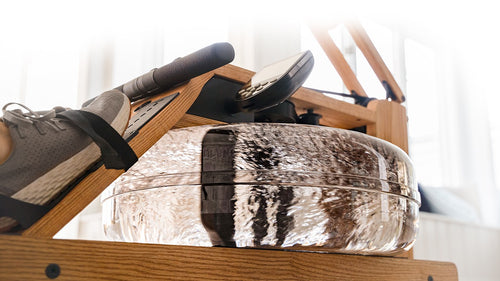 Rowing machine with a person's foot on the paddle, showing the movement of the rowing motion.