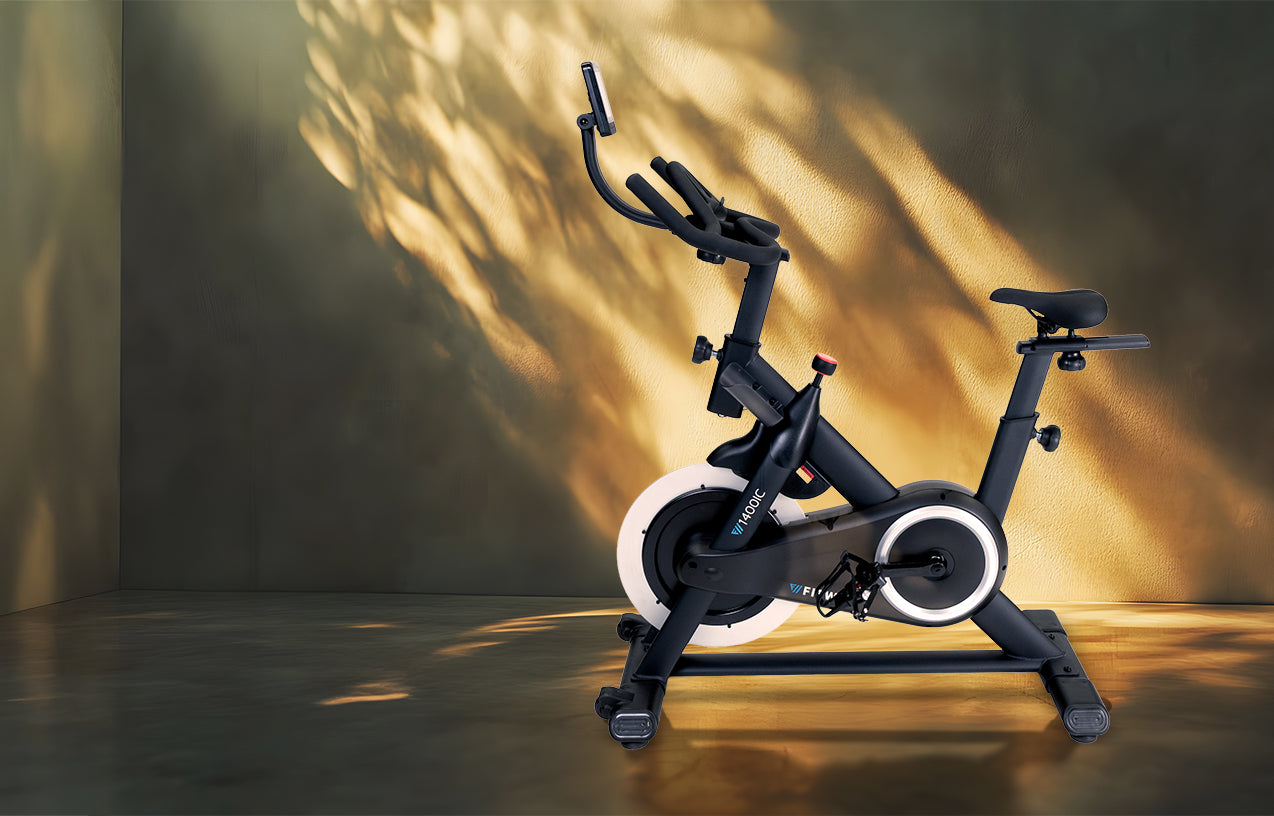 Black exercise bike on a dark floor with a warm light source casting shadows on the wall.