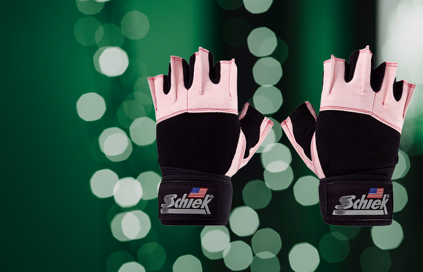 Pair of black and pink gloves with 'Schiek' branding on a green bokeh background