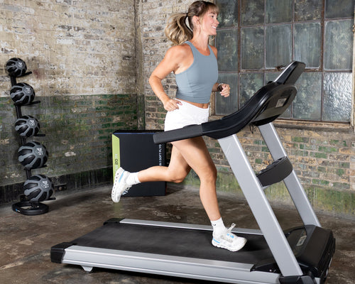 Woman running on a treadmill in a gym setting