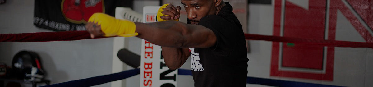 Boxer in a black shirt and yellow gloves training in a boxing ring.
