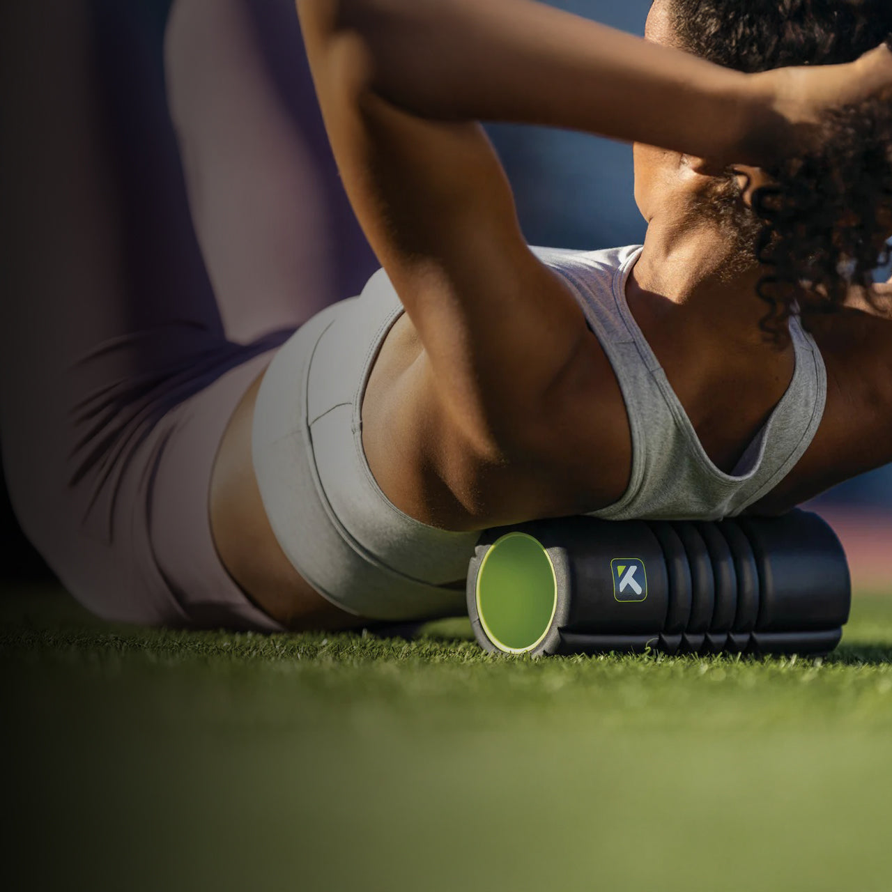 Person using a blue foam roller on the lawn