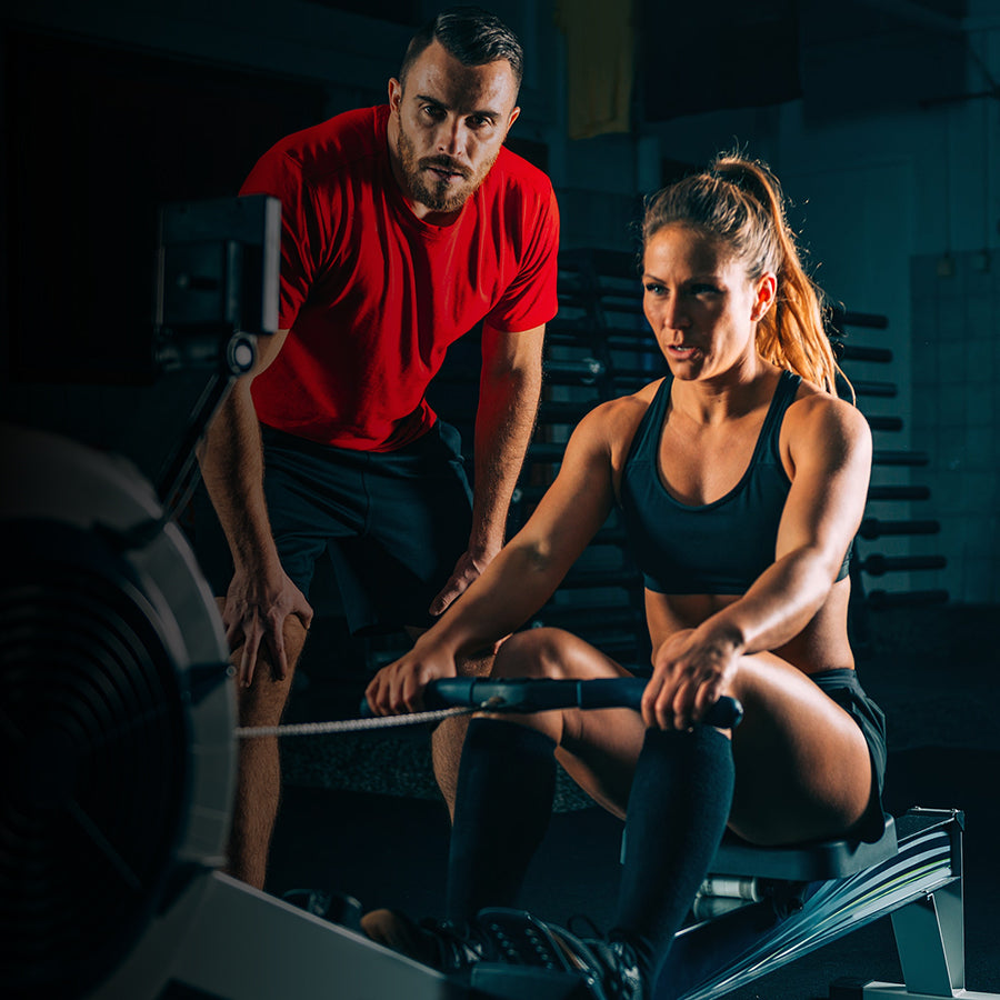 Person using a Fitway air rowing machine with another person observing in a gym setting