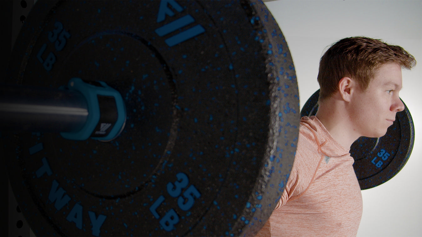 Person lifting a barbell with weights on a light background