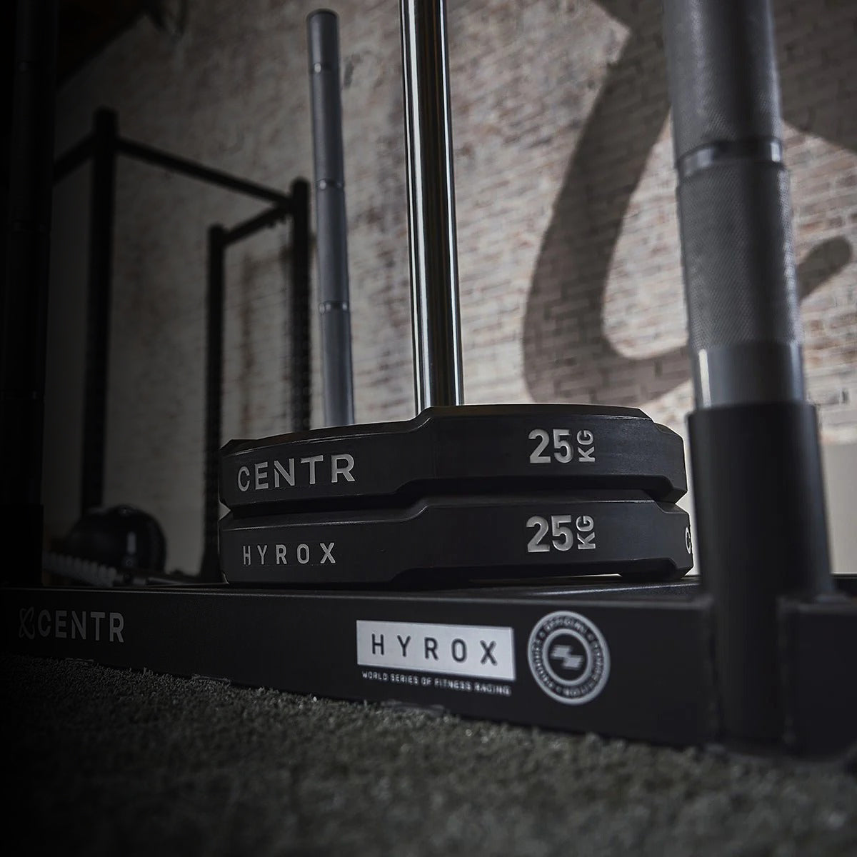 Barbell with weight plates labeled 'Hyrox' in a gym setting