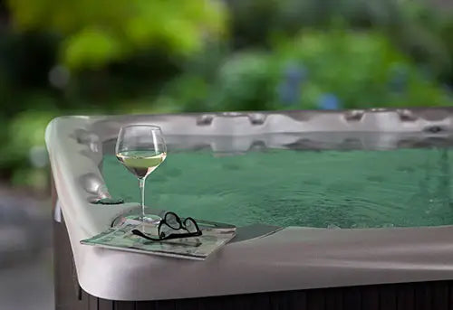 Glass of white wine on a hot tub with a blurred garden background