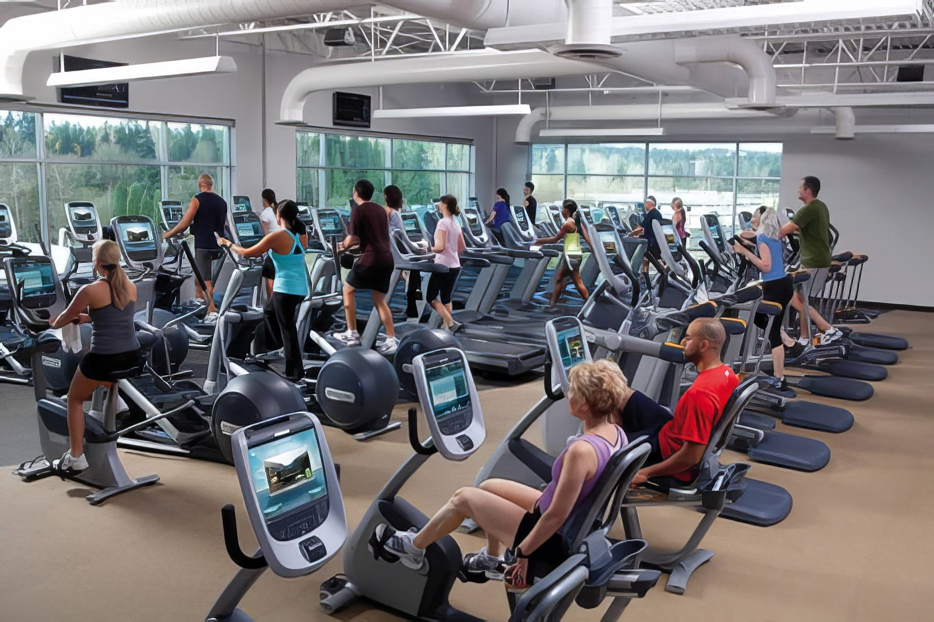 Gym interior with people using exercise equipment and large windows.