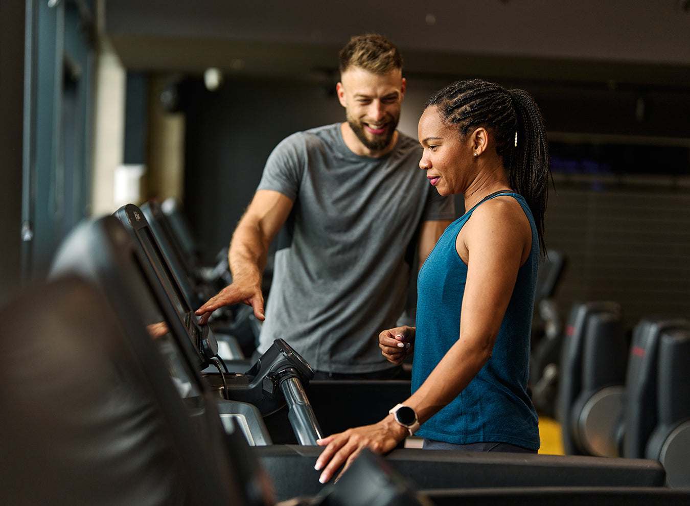 Two people using treadmills in a gym setting