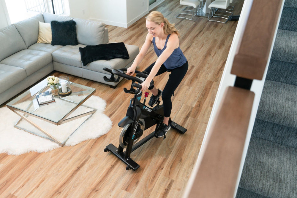 Woman exercising on a stationary bike in a living room.