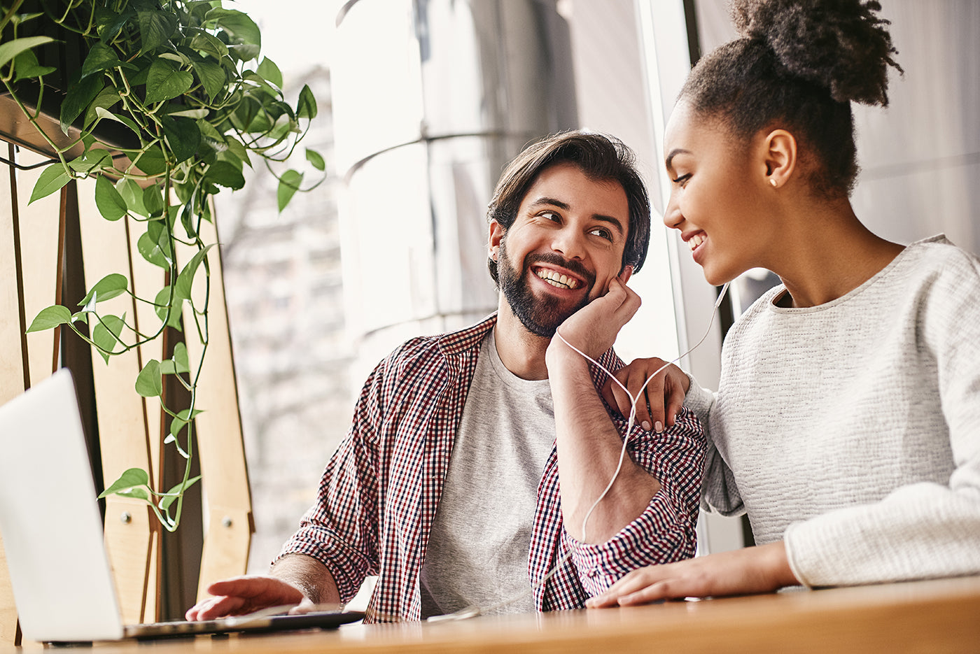 Man and woman sitting together at a desk with a laptop, engaged in conversation.