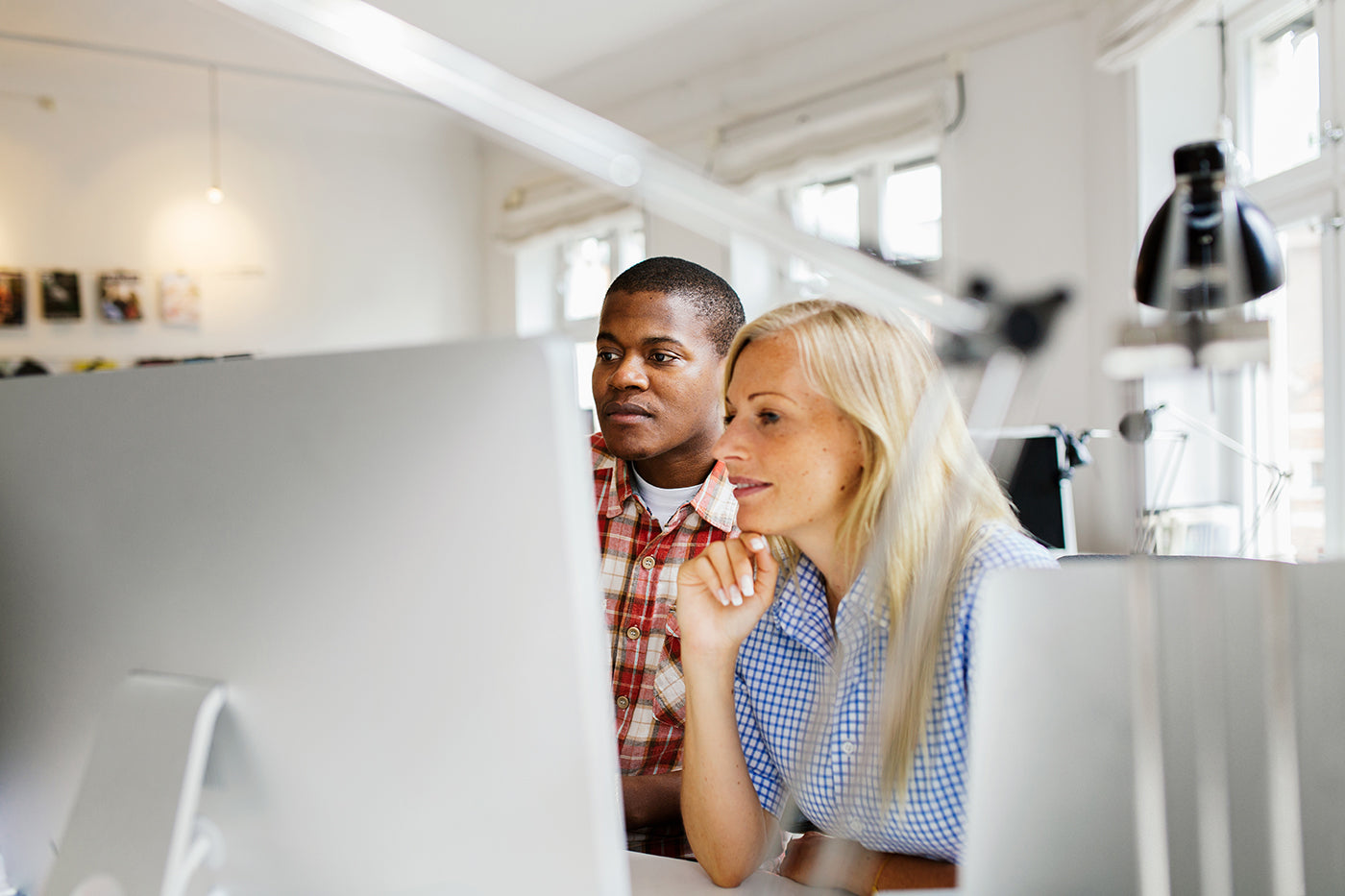 Two people looking at a computer screen in an office setting