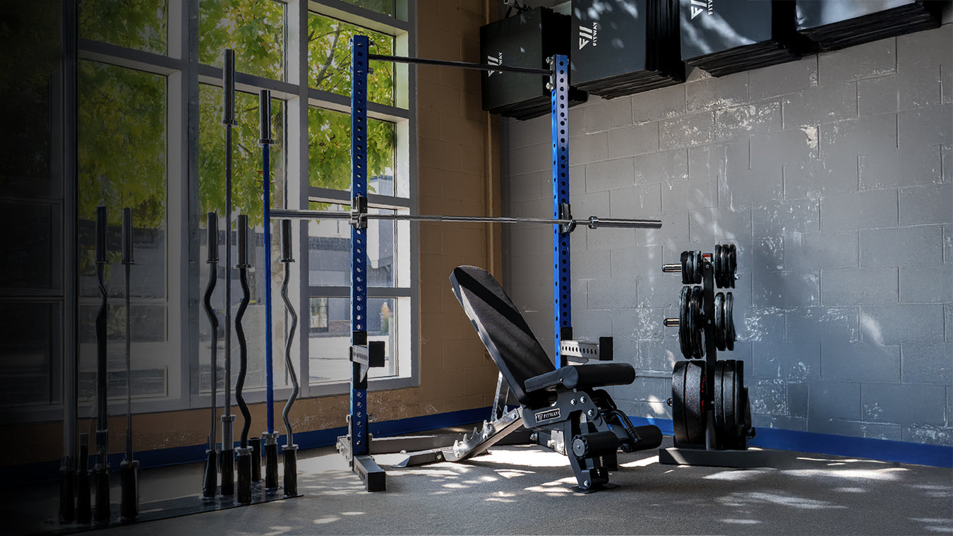 Gym equipment including a Fitway weight bench,barbell and rack in a room with large windows.