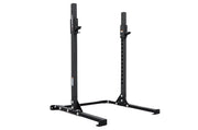 Two black low squat racks with textured powder coat paint, standing upright in a gray area, presumably a warehouse setting.